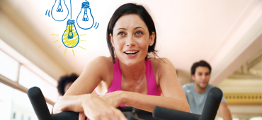 Lachende Frau auf dem Fahrrad im Fitnessstudio